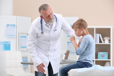 Coughing little boy visiting doctor at clinic