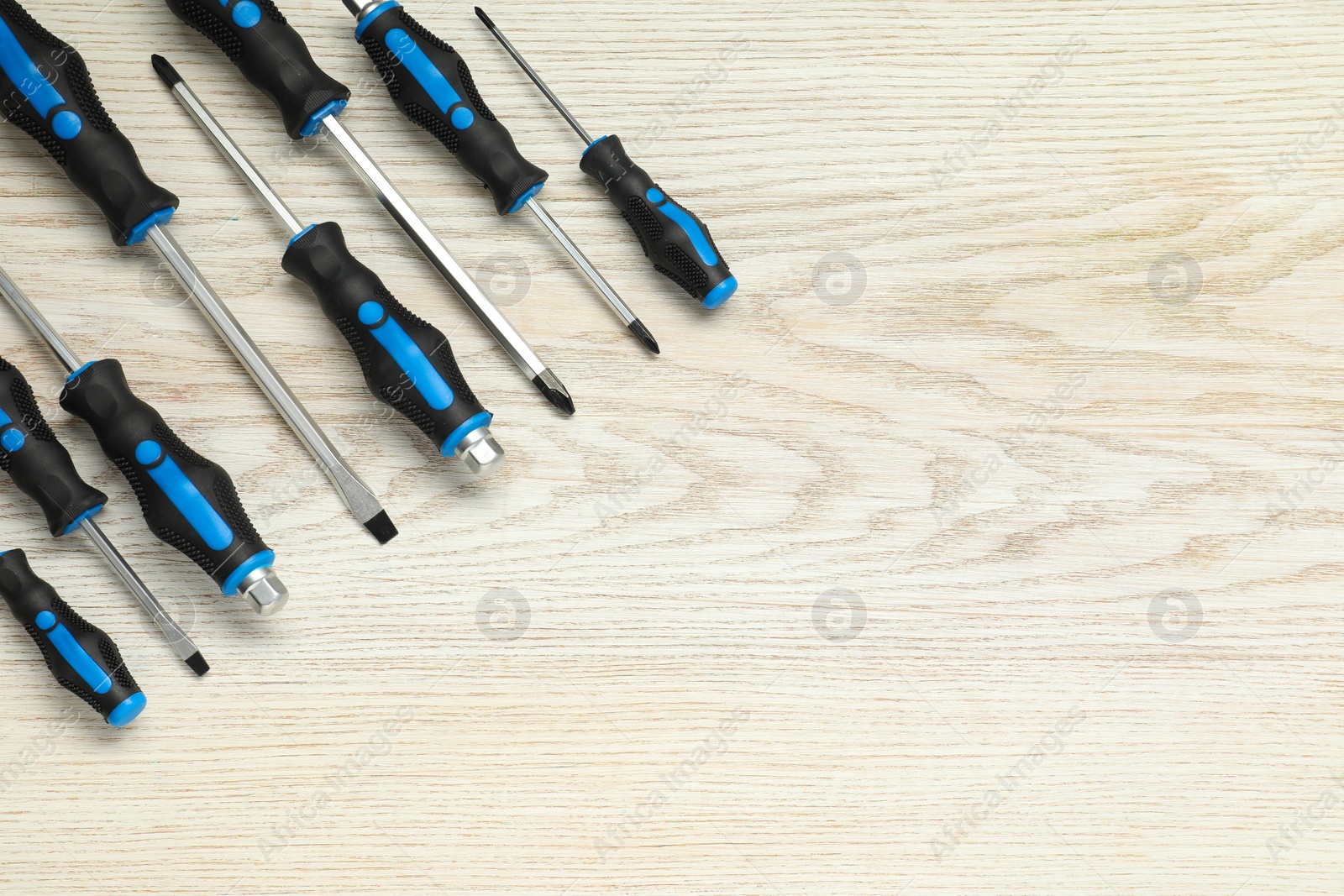 Photo of Set of screwdrivers on white wooden table, top view. Space for text