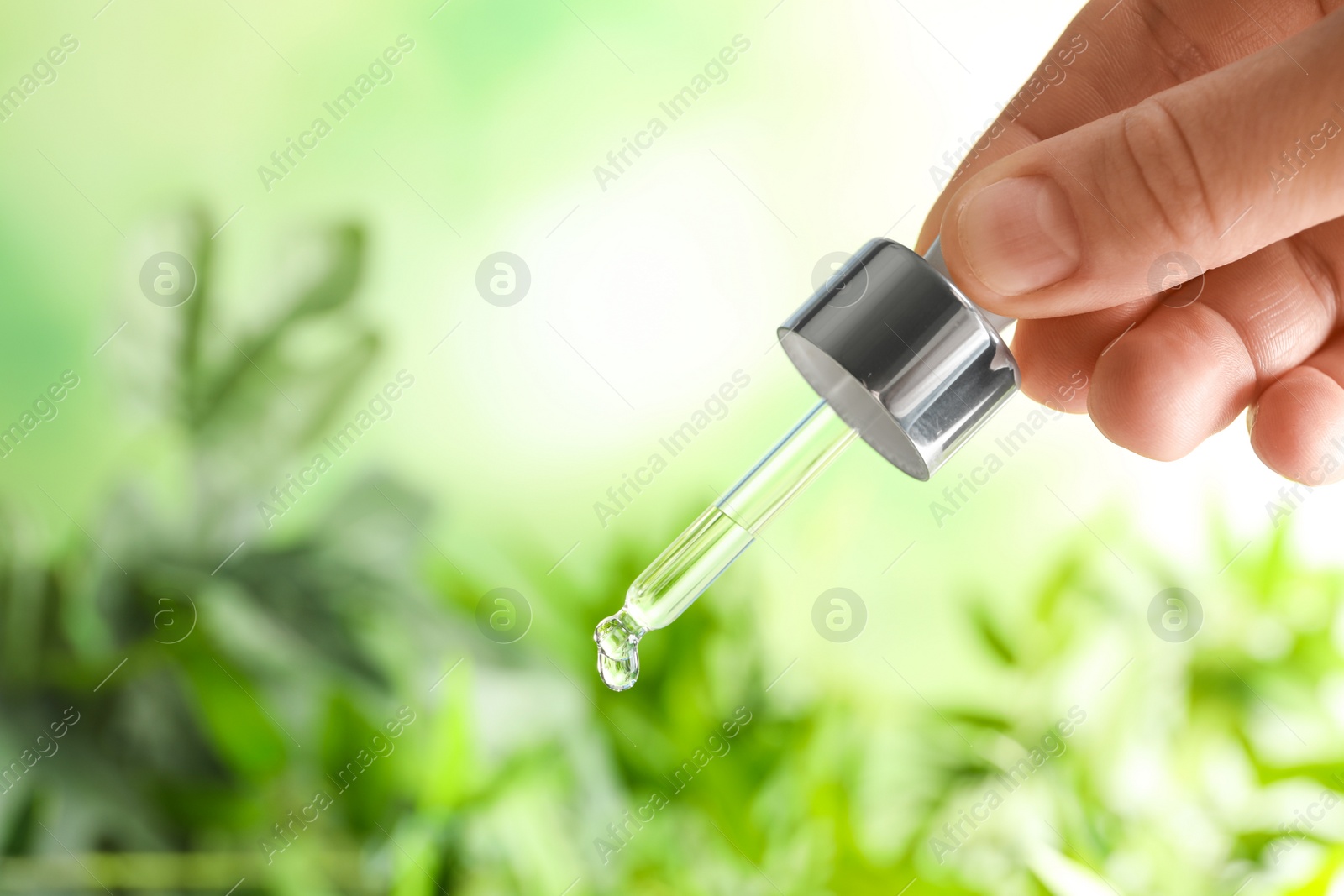 Photo of Woman holding pipette with oil on blurred background. Space for text