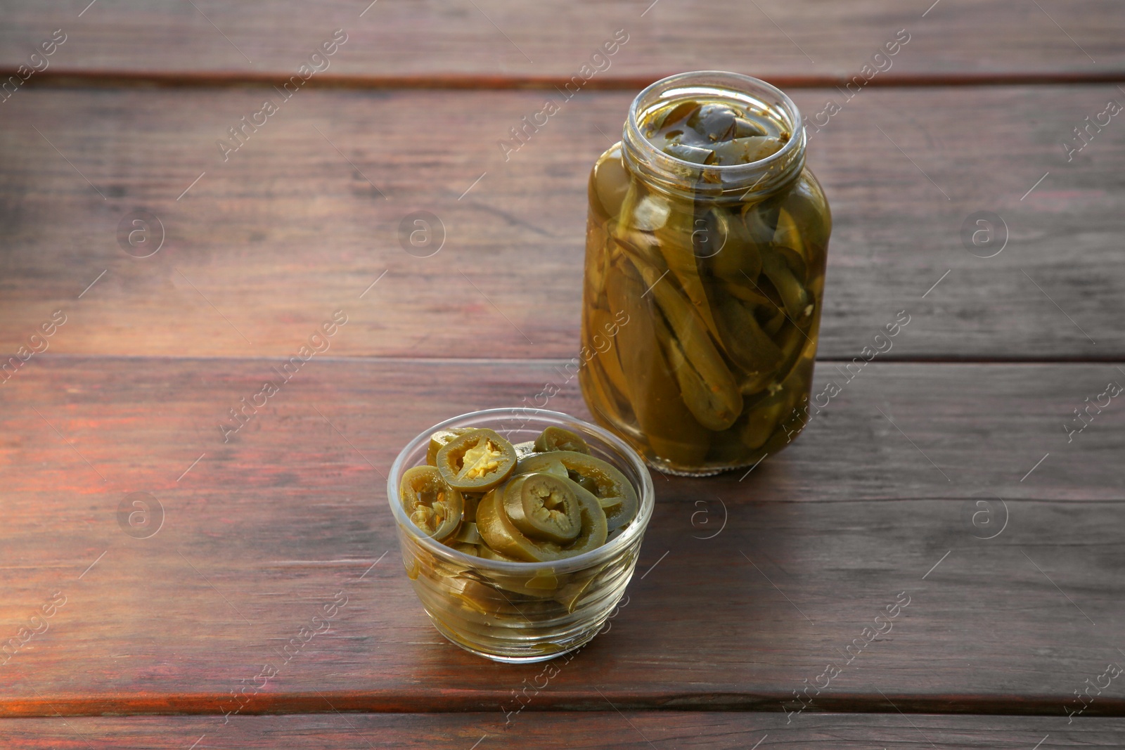 Photo of Pickled green jalapeno peppers on wooden table. Space for text