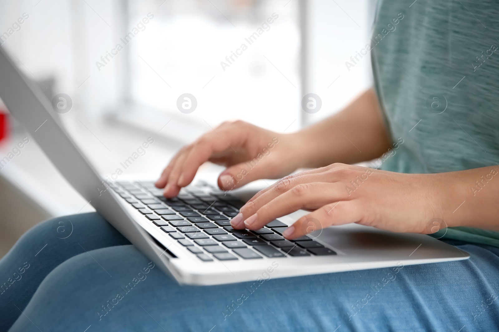 Photo of Young woman using laptop indoors, closeup