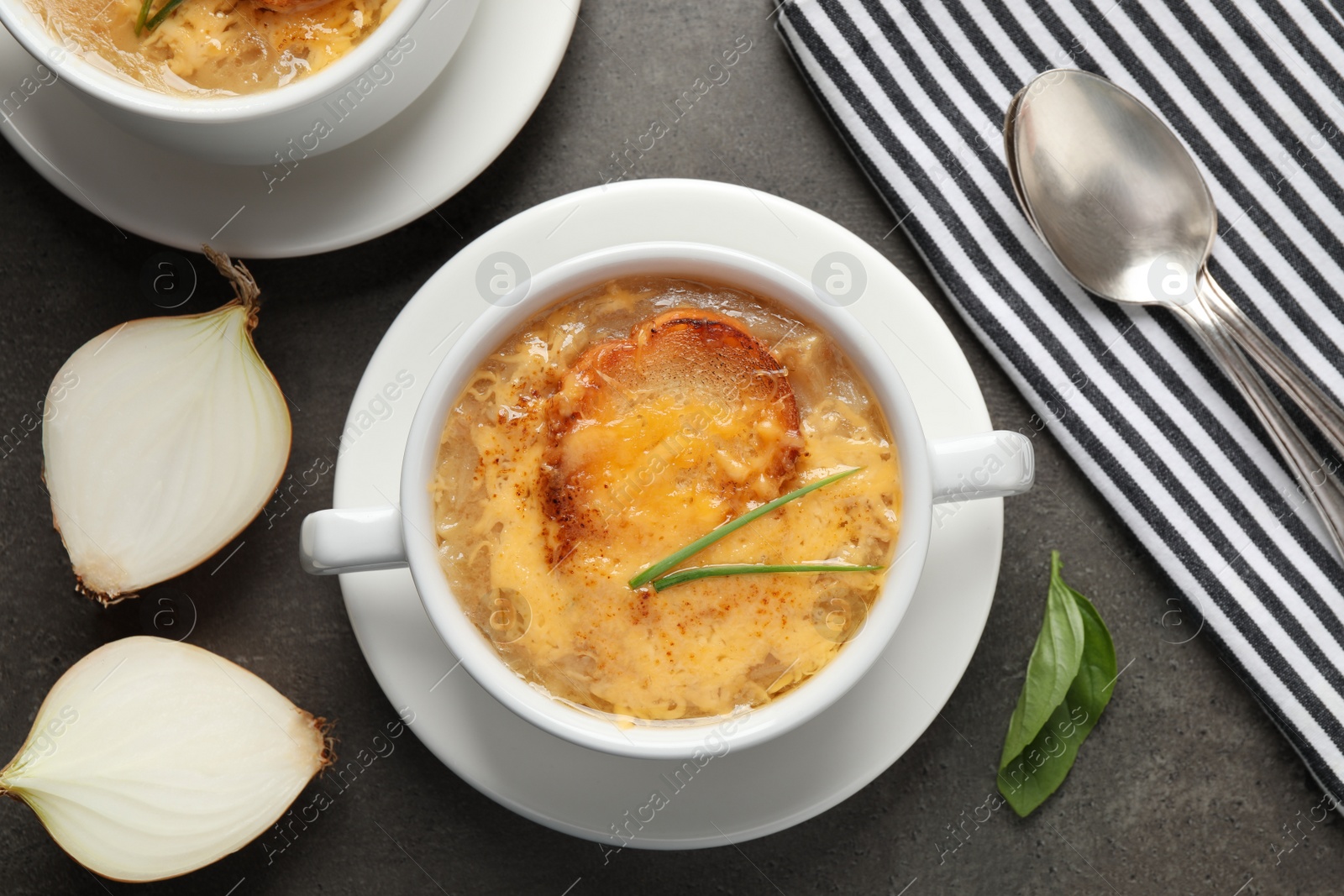 Photo of Tasty homemade french onion soup served on grey table, flat lay