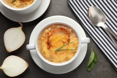 Photo of Tasty homemade french onion soup served on grey table, flat lay