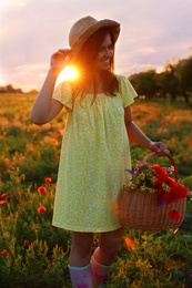 Photo of Woman with basket of poppies and wildflowers in beautiful field at sunset