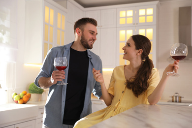 Photo of Lovely young couple drinking wine while cooking together in kitchen