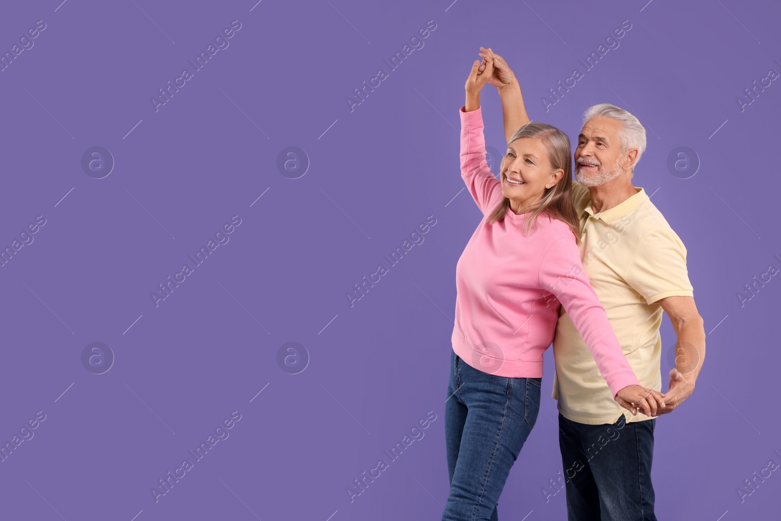 Photo of Senior couple dancing together on purple background, space for text