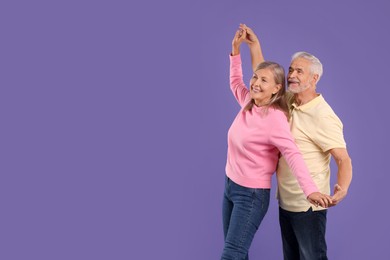 Senior couple dancing together on purple background, space for text