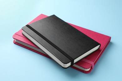 Photo of Black and pink notebooks on light blue background