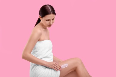 Photo of Beautiful woman with smear of body cream on her leg against pink background, space for text