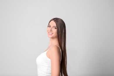 Portrait of young woman with long beautiful hair on light background