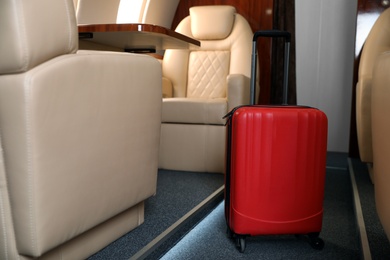Airplane cabin with red suitcase. Air travel