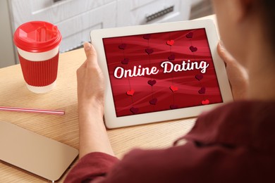 Woman visiting dating site via tablet at wooden table indoors, closeup