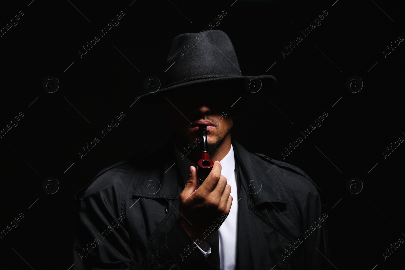 Photo of Old fashioned detective with smoking pipe on dark background