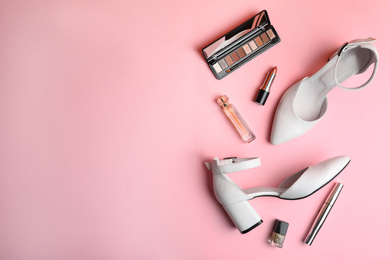 Photo of Stylish white female shoes and decorative cosmetics on pink background, flat lay. Space for text