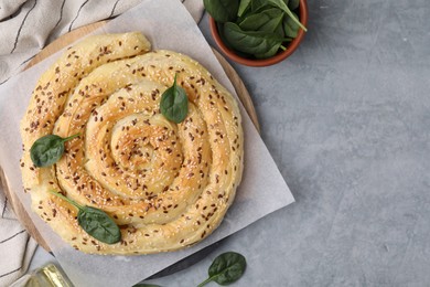 Photo of Delicious puff pastry with spinach on grey table, flat lay. Space for text