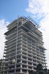 Multistory building under construction against cloudy sky, low angle view