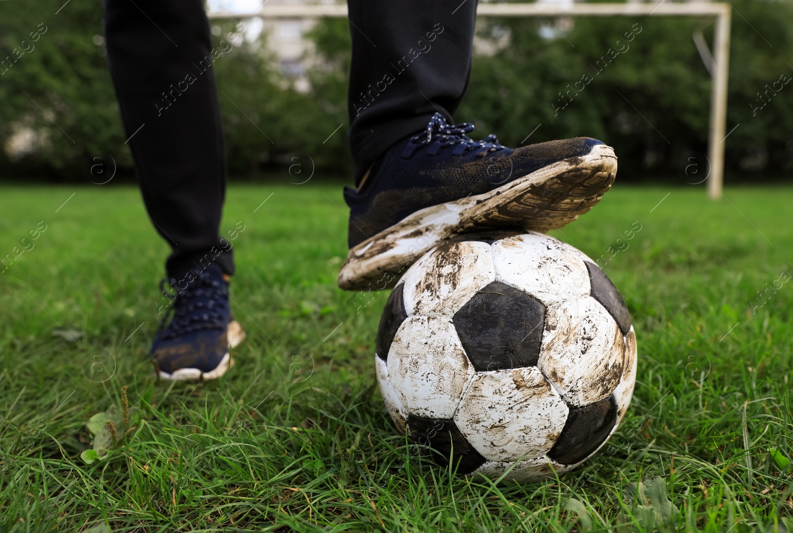 Photo of Man with dirty soccer ball on green grass outdoors, closeup