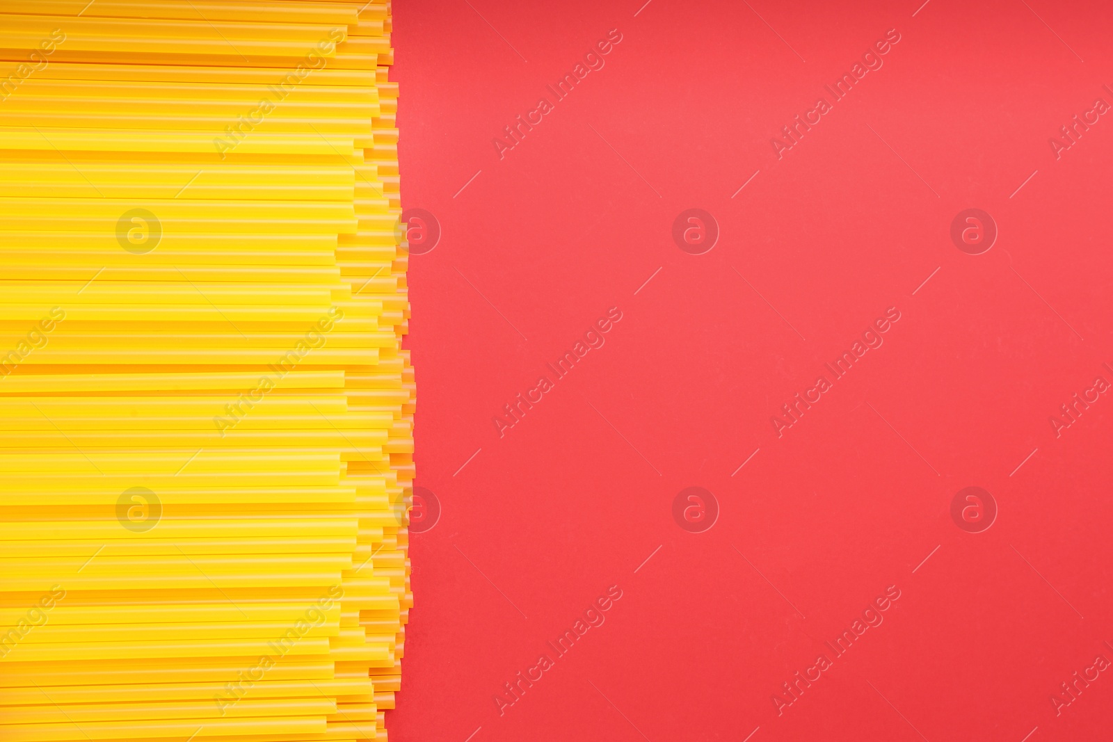 Photo of Yellow plastic drinking straws on red background, flat lay. Space for text