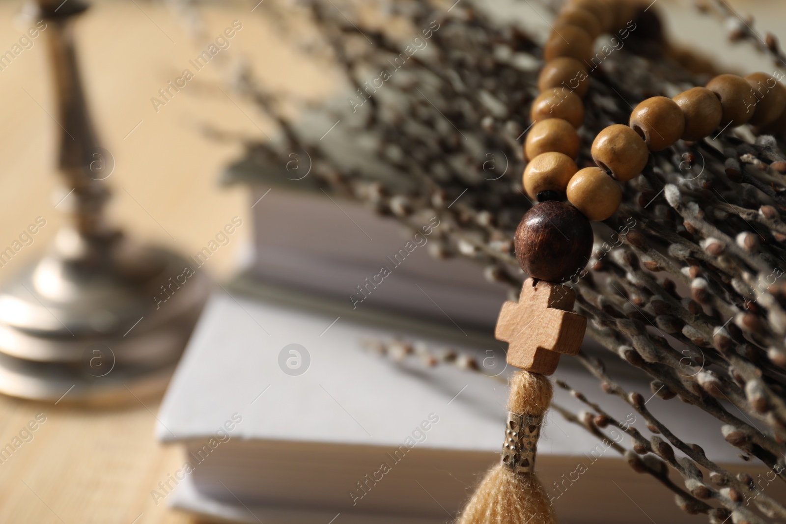 Photo of Rosary beads, willow branches and books on table, closeup. Space for text