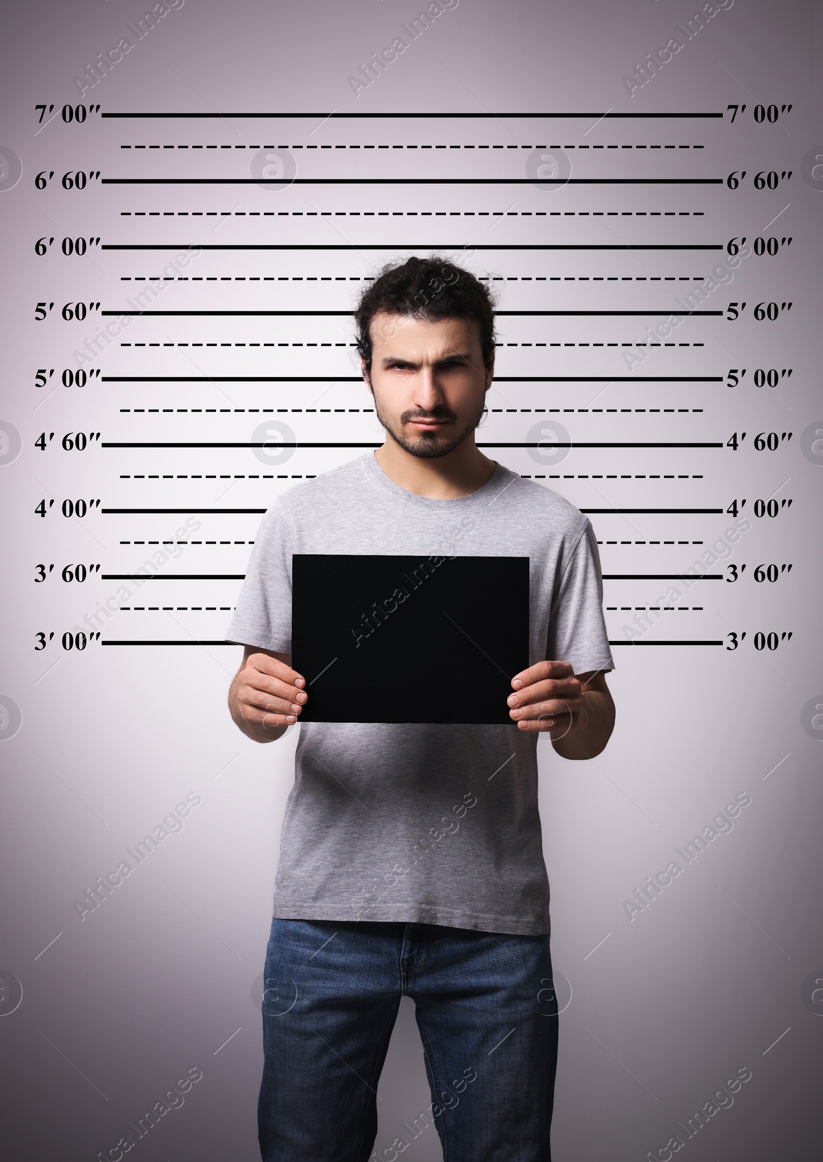 Image of Criminal mugshot. Arrested man with blank card against height chart