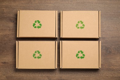 Image of Cardboard boxes with recycle sign stamps on wooden background, flat lay