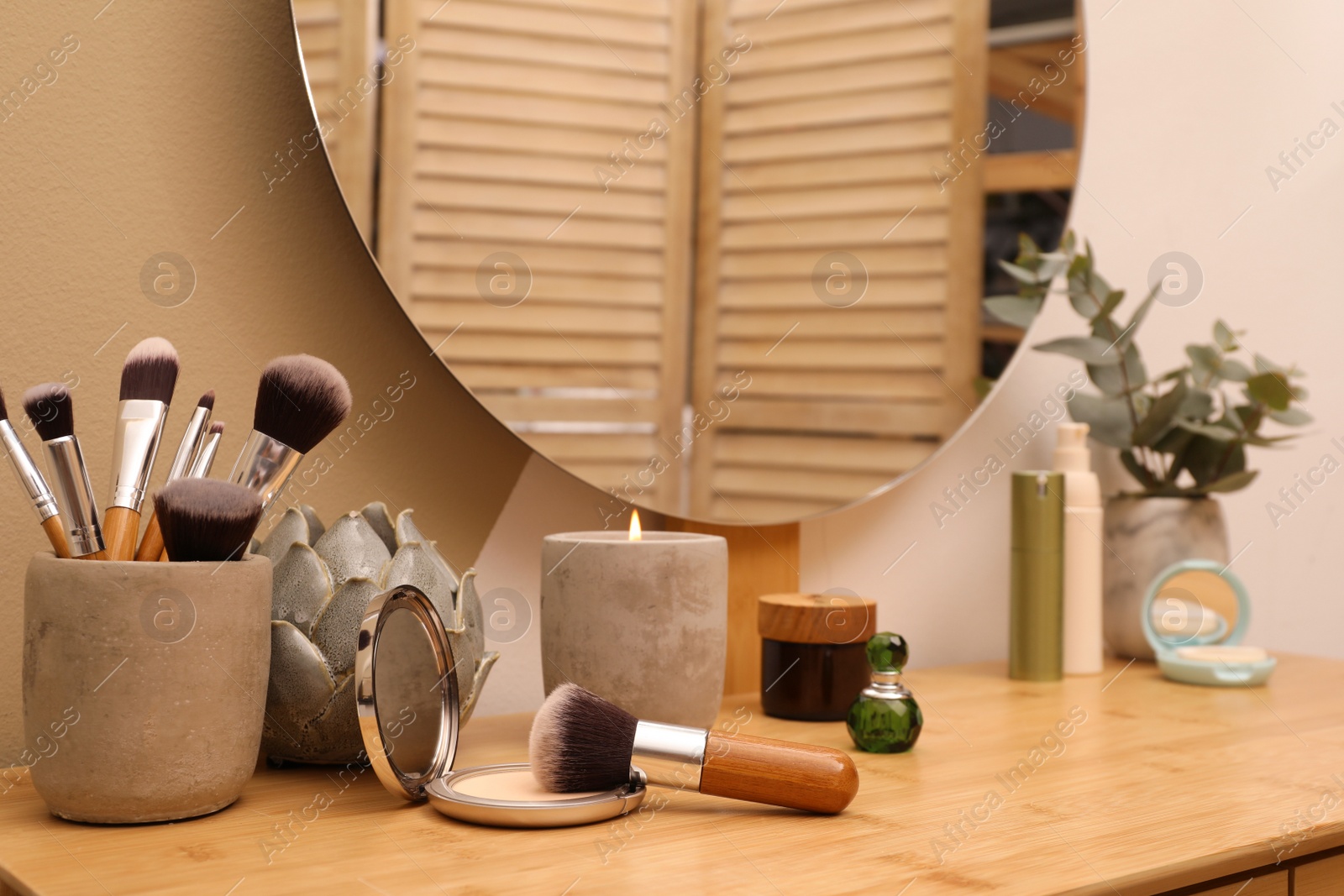 Photo of Wooden dressing table with round mirror and makeup products