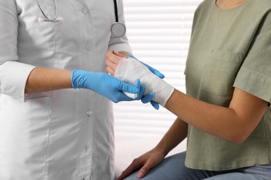 Doctor bandaging patient's burned hand indoors, closeup