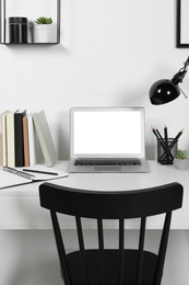 Photo of Cozy workspace with computer, lamp and stationery on wooden desk at home