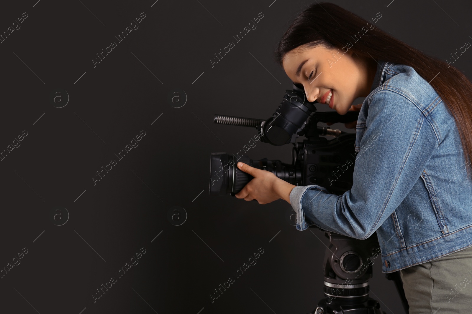 Photo of Operator with professional video camera on black background, space for text