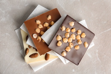 Photo of Different chocolate bars with nuts on grey background