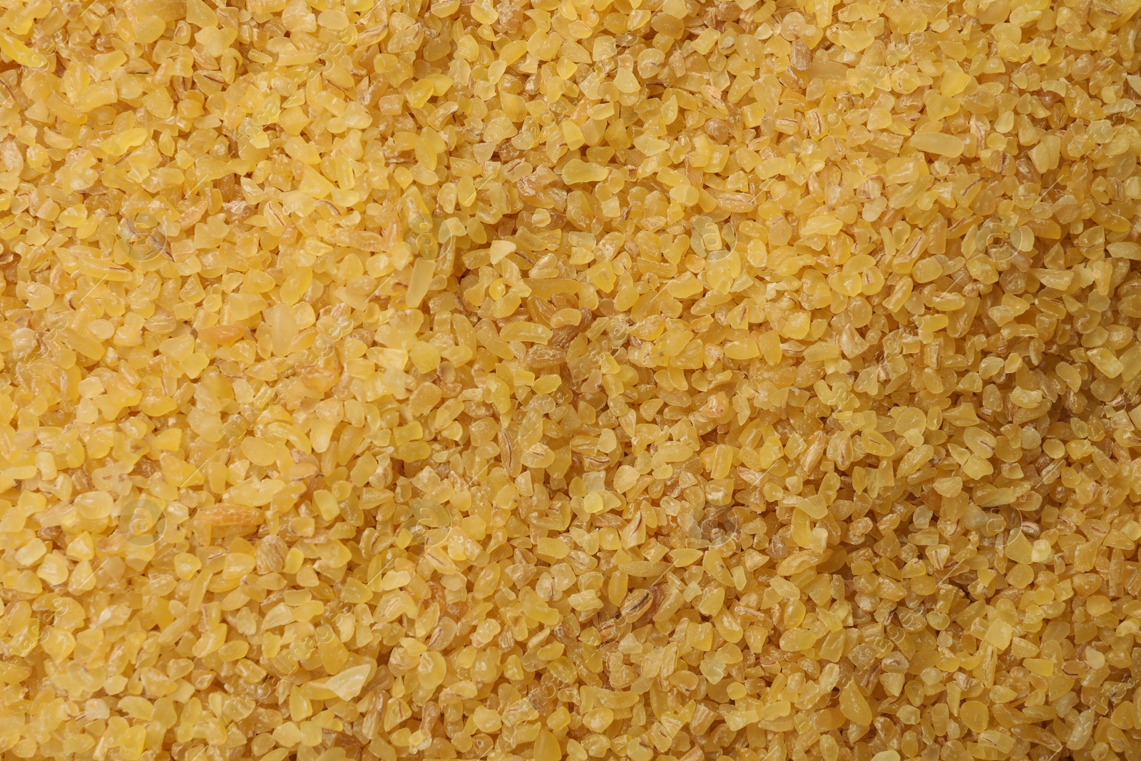 Photo of Pile of raw bulgur as background, top view