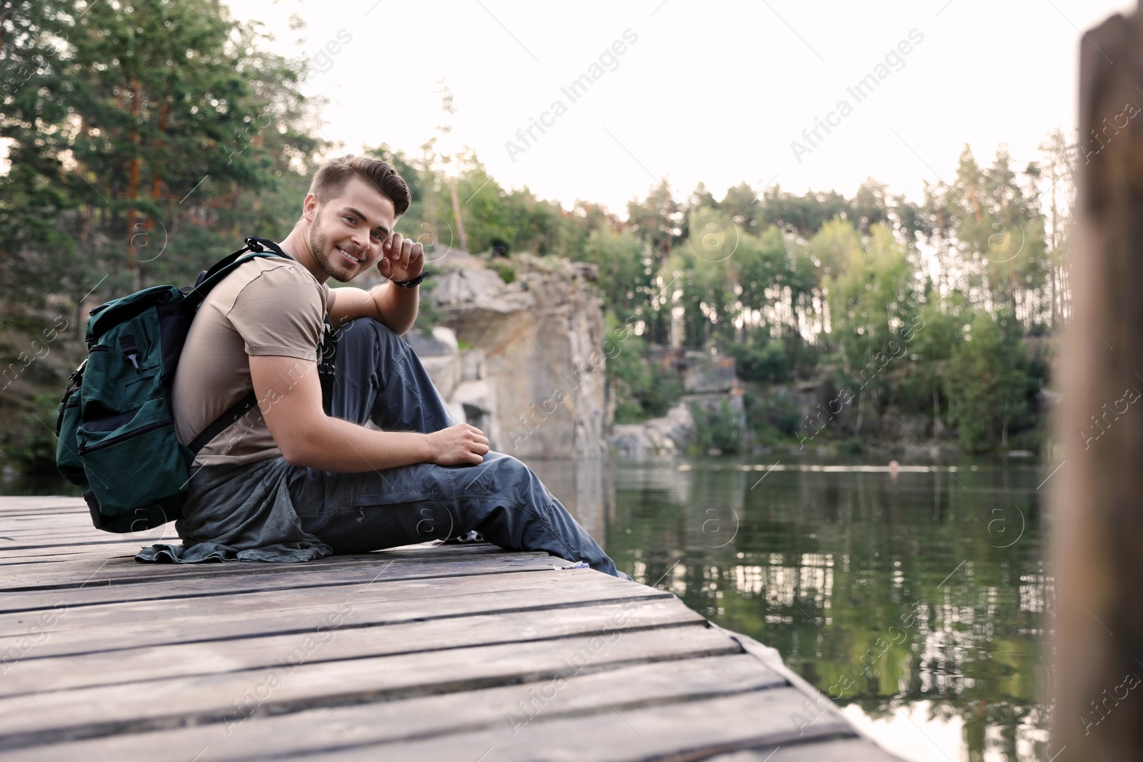 Photo of Young man on wooden pier near lake. Camping season