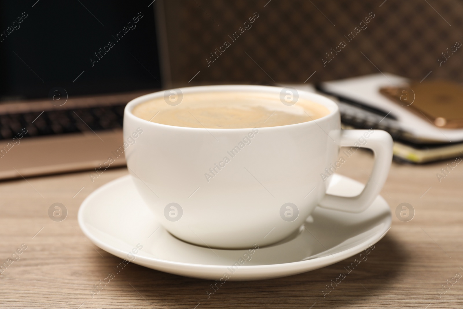 Photo of Coffee Break at workplace. Cup of hot drink on wooden table