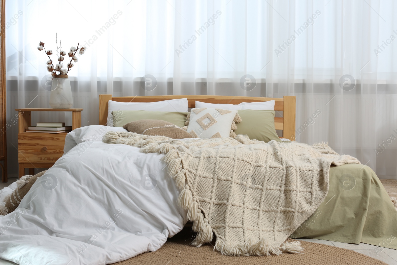 Photo of Large comfortable bed with soft pillows, duvet and blanket in room. Home textile