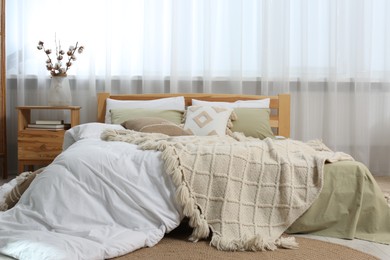 Photo of Large comfortable bed with soft pillows, duvet and blanket in room. Home textile