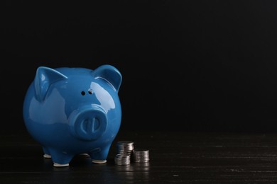 Photo of Financial savings. Piggy bank and coins on wooden table, space for text