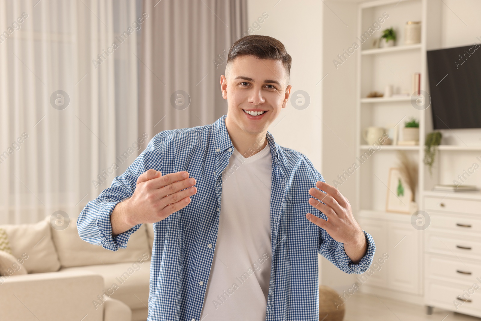 Photo of Handsome man inviting to come in room at home