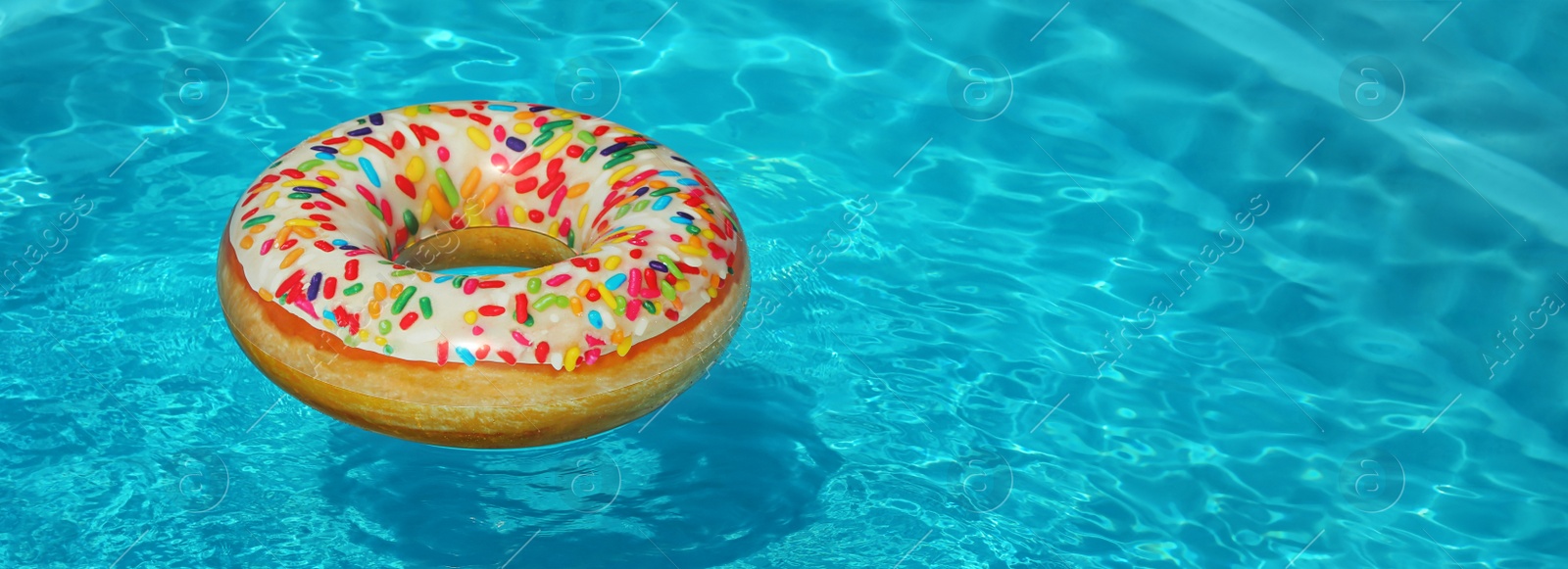 Image of Bright inflatable doughnut ring floating in swimming pool on sunny day, space for text. Banner design