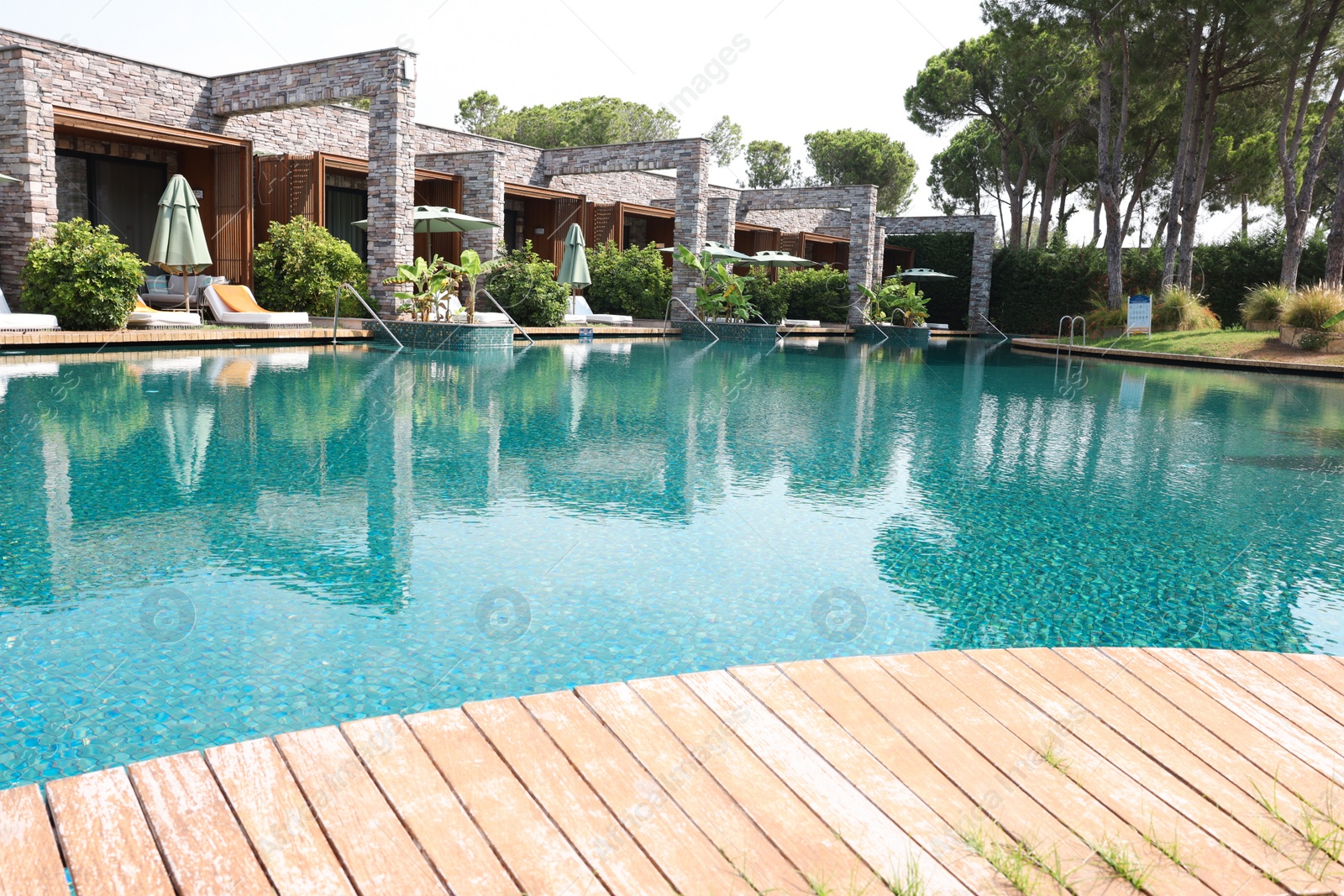 Photo of Outdoor swimming pool with wooden deck, umbrellas and sunbeds at resort