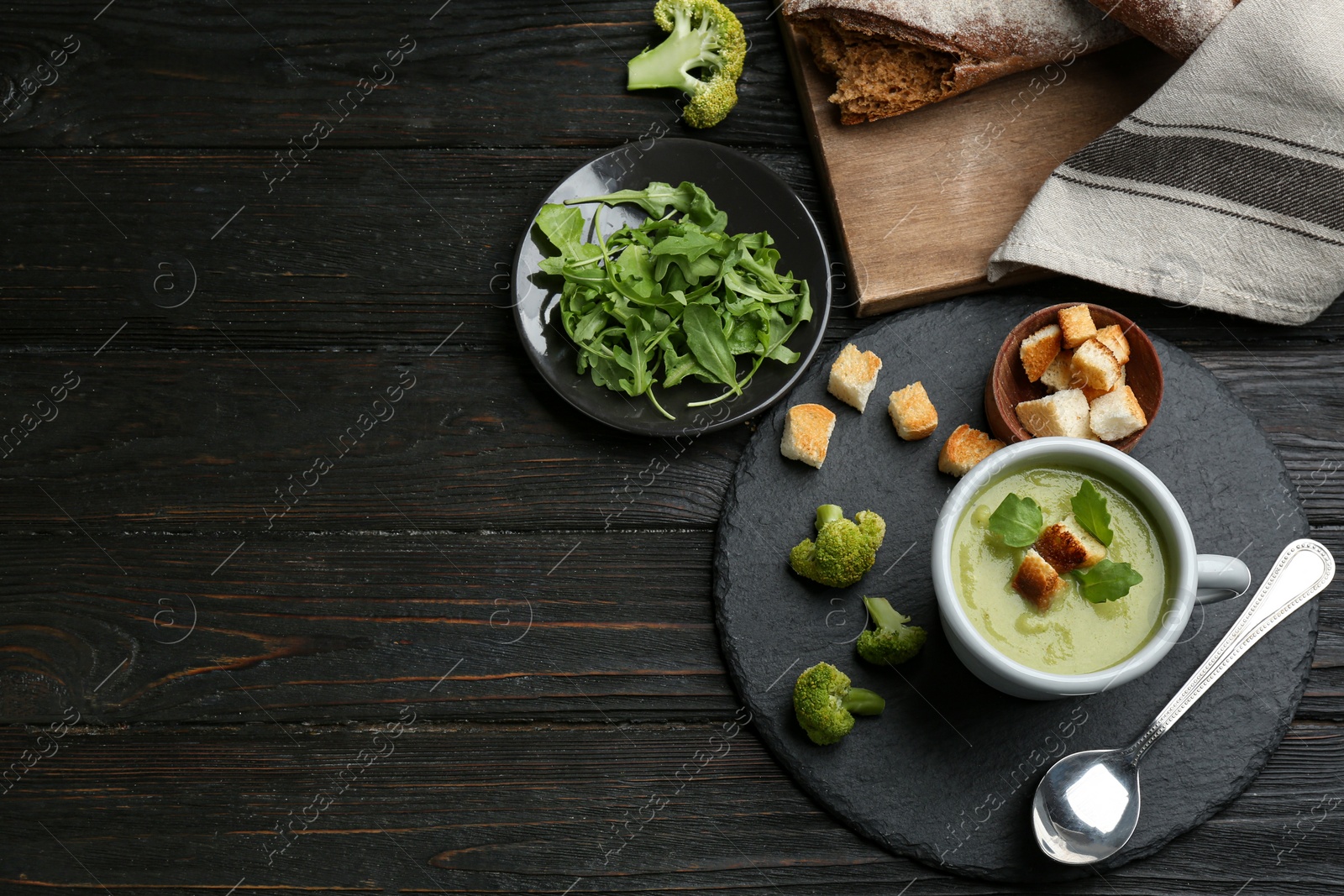 Photo of Flat lay composition with cup of broccoli cream soup on black wooden table, space for text