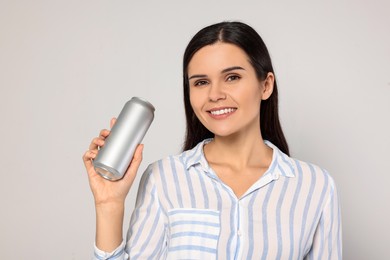 Photo of Beautiful young woman holding tin can with beverage on light grey background