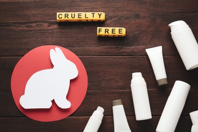 Photo of Cubes with text Cruelty Free, personal care products and figure of rabbit on wooden table, flat lay. Stop animal tests
