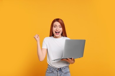 Photo of Happy young woman with laptop on yellow background