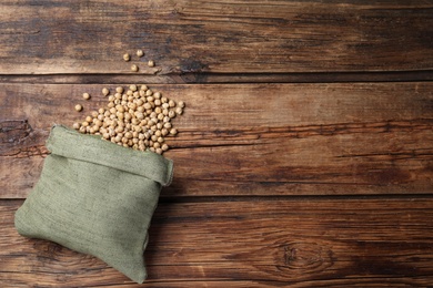 Photo of Sack with chickpeas on wooden table, flat lay. Space for text