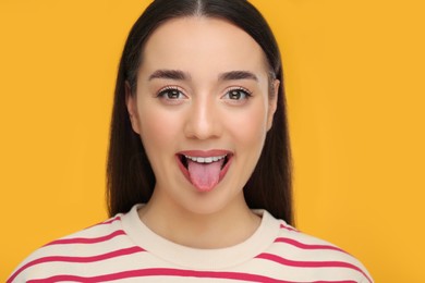 Photo of Happy woman showing her tongue on orange background