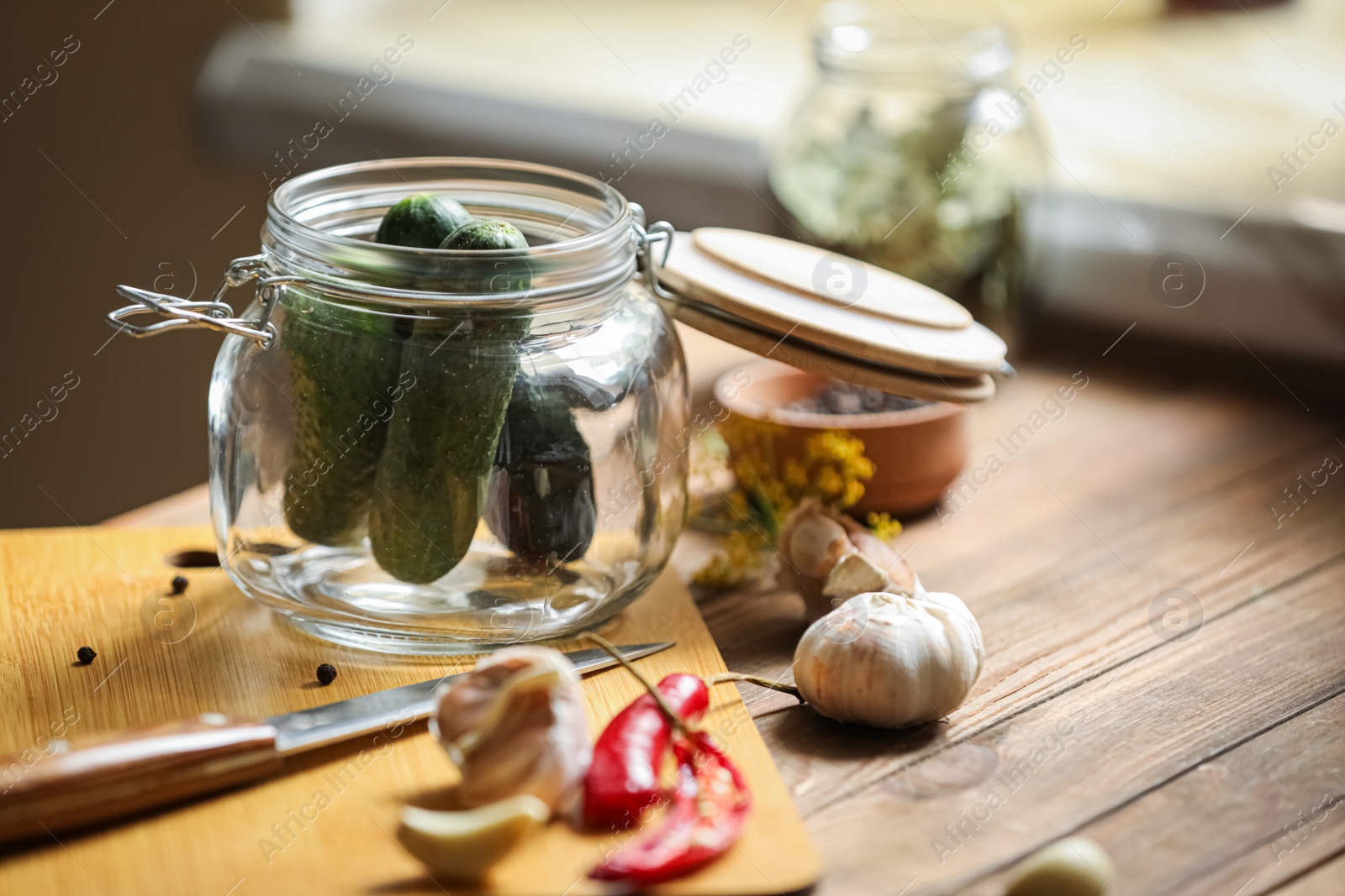 Photo of Glass jar with fresh cucumbers and other ingredients on wooden table, space for text. Pickling vegetables