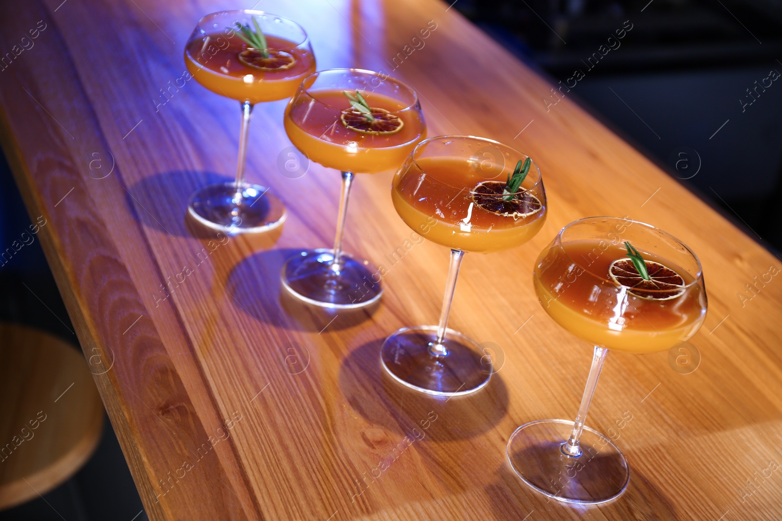 Photo of Glasses of delicious cocktail with vodka on wooden counter in bar