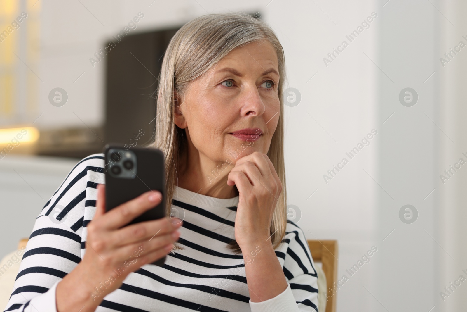 Photo of Senior woman using mobile phone at home, space for text