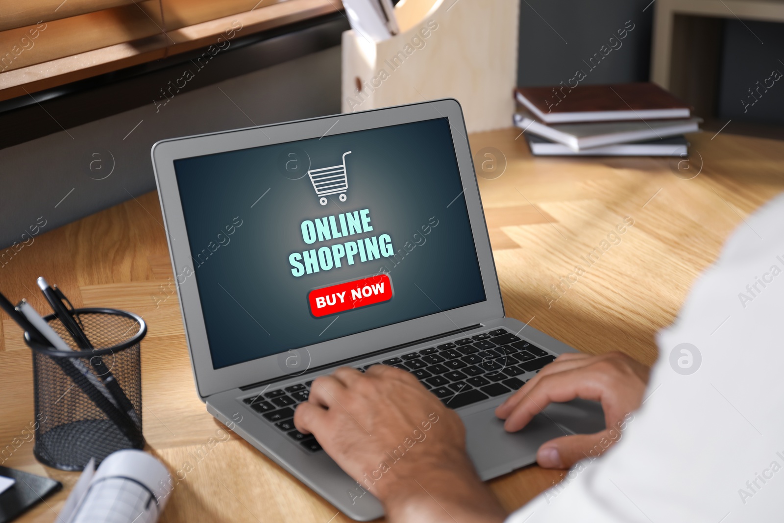 Image of Man using laptop for online shopping at wooden table, closeup