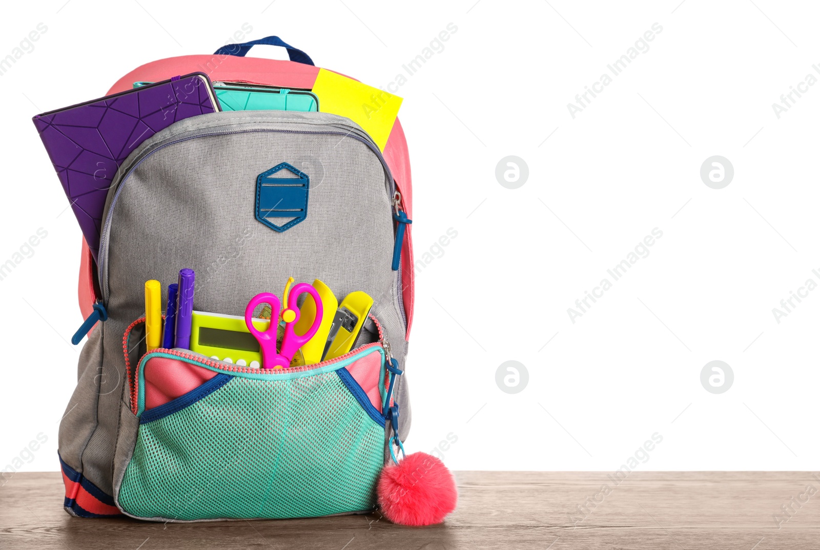 Photo of Bright backpack with school stationery on wooden table against white background